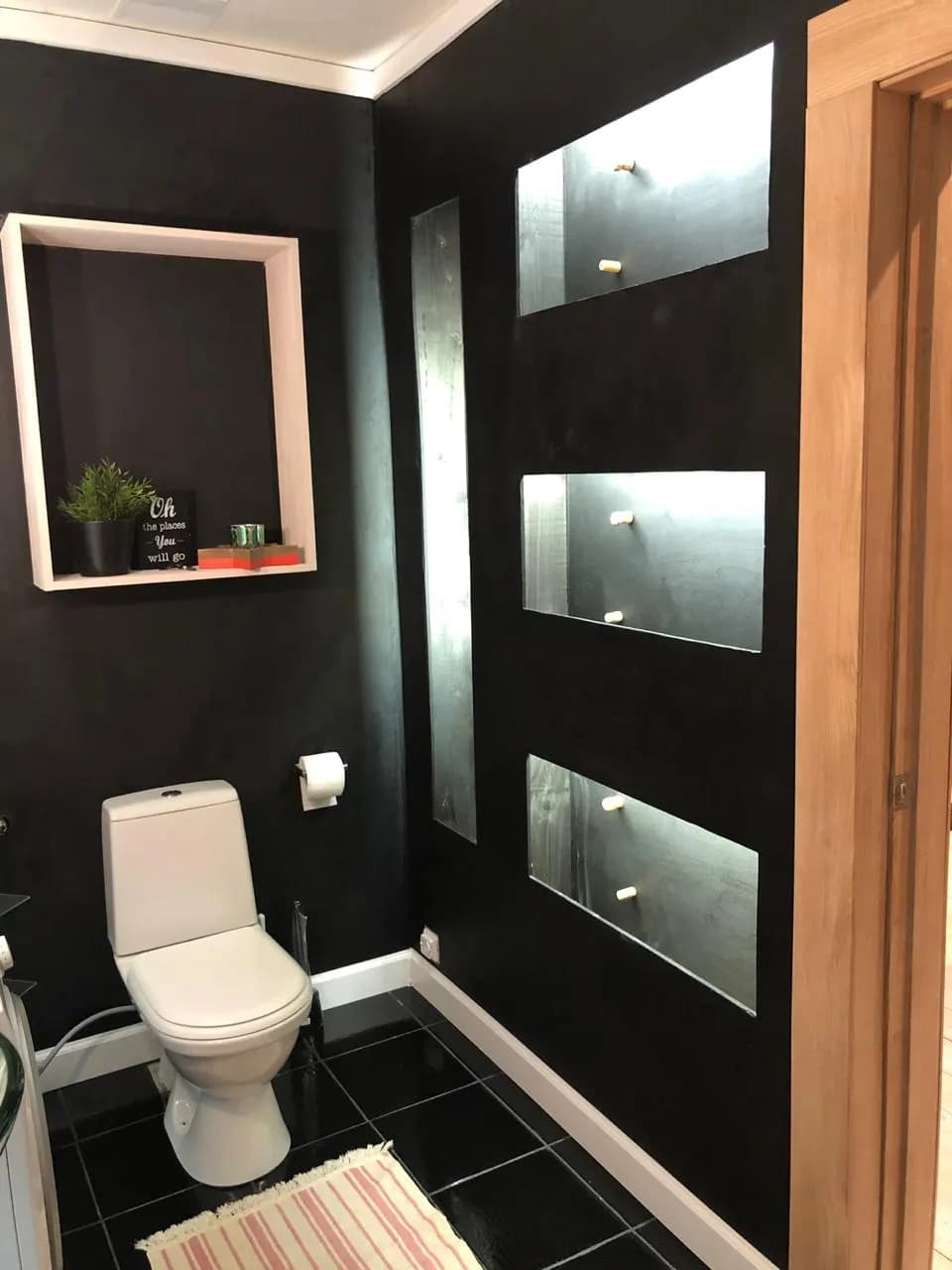 Matte-black wall with a lit display niche and steel panel details