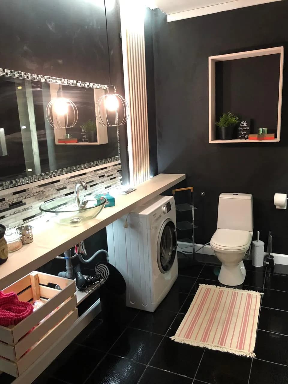 Black bathroom with a glass vessel sink, mosaic backsplash, caged sconce lights, and a washer under the counter