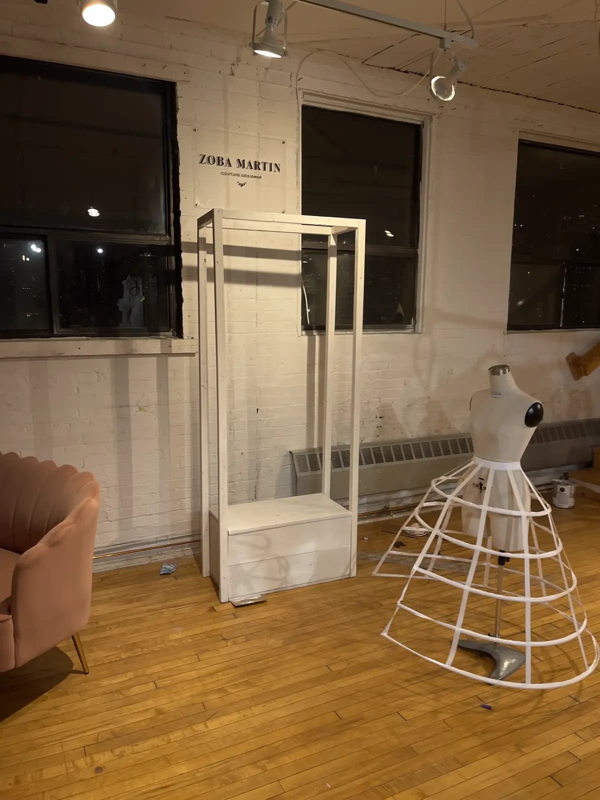 Raw loft space mid build-out, with bare walls, display frames, and an unfinished dress-form stand
