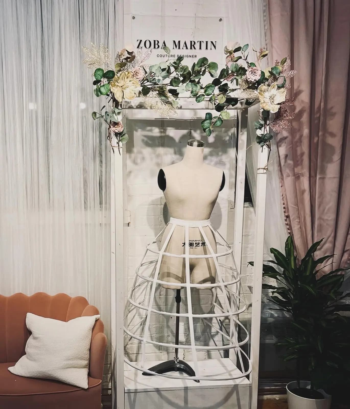 The same display corner finished with a styled dress form, florals, and sheer drapery