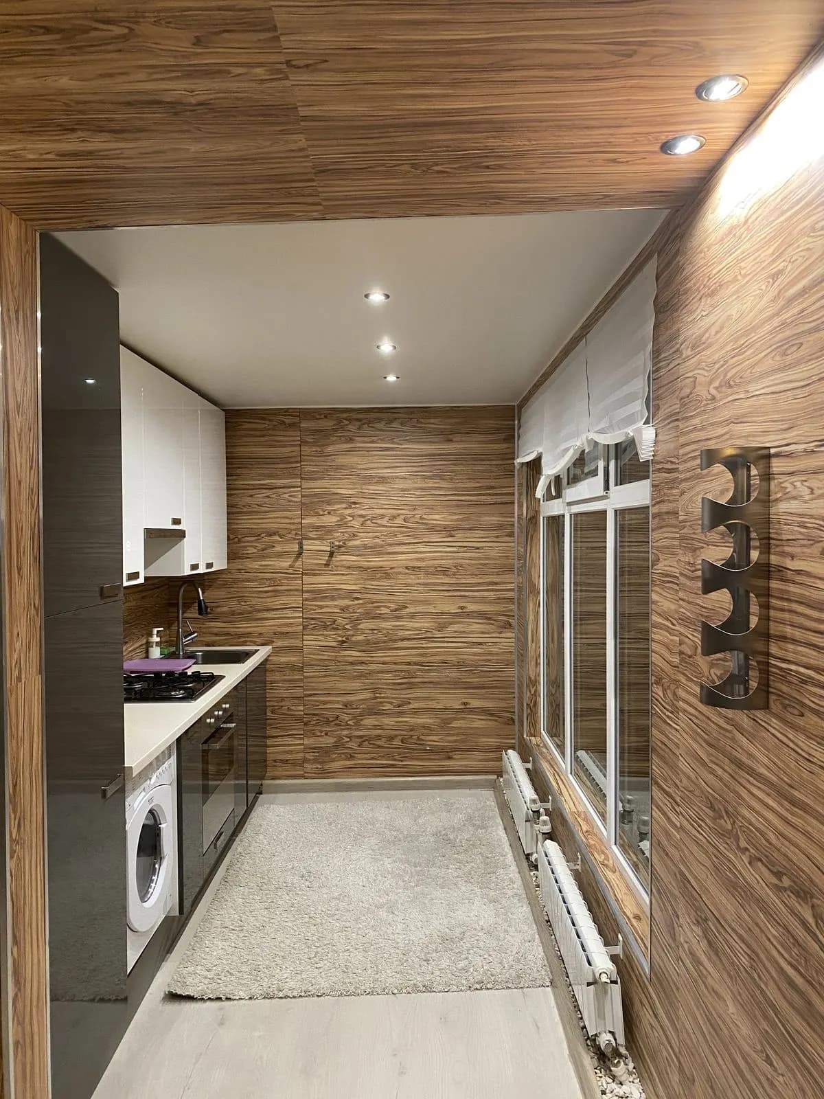 Compact kitchen with glossy white uppers and walnut wall panelling