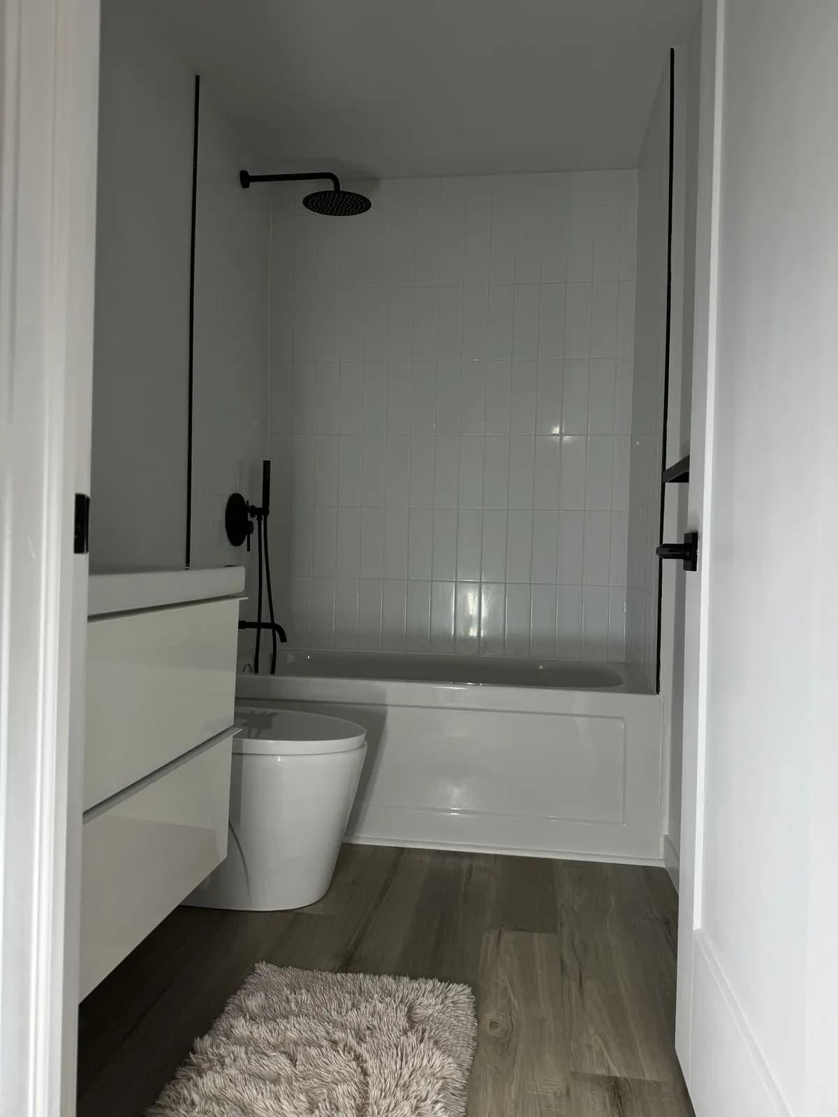 New bathroom with a white tub, subway-tile surround, and matte-black rain shower
