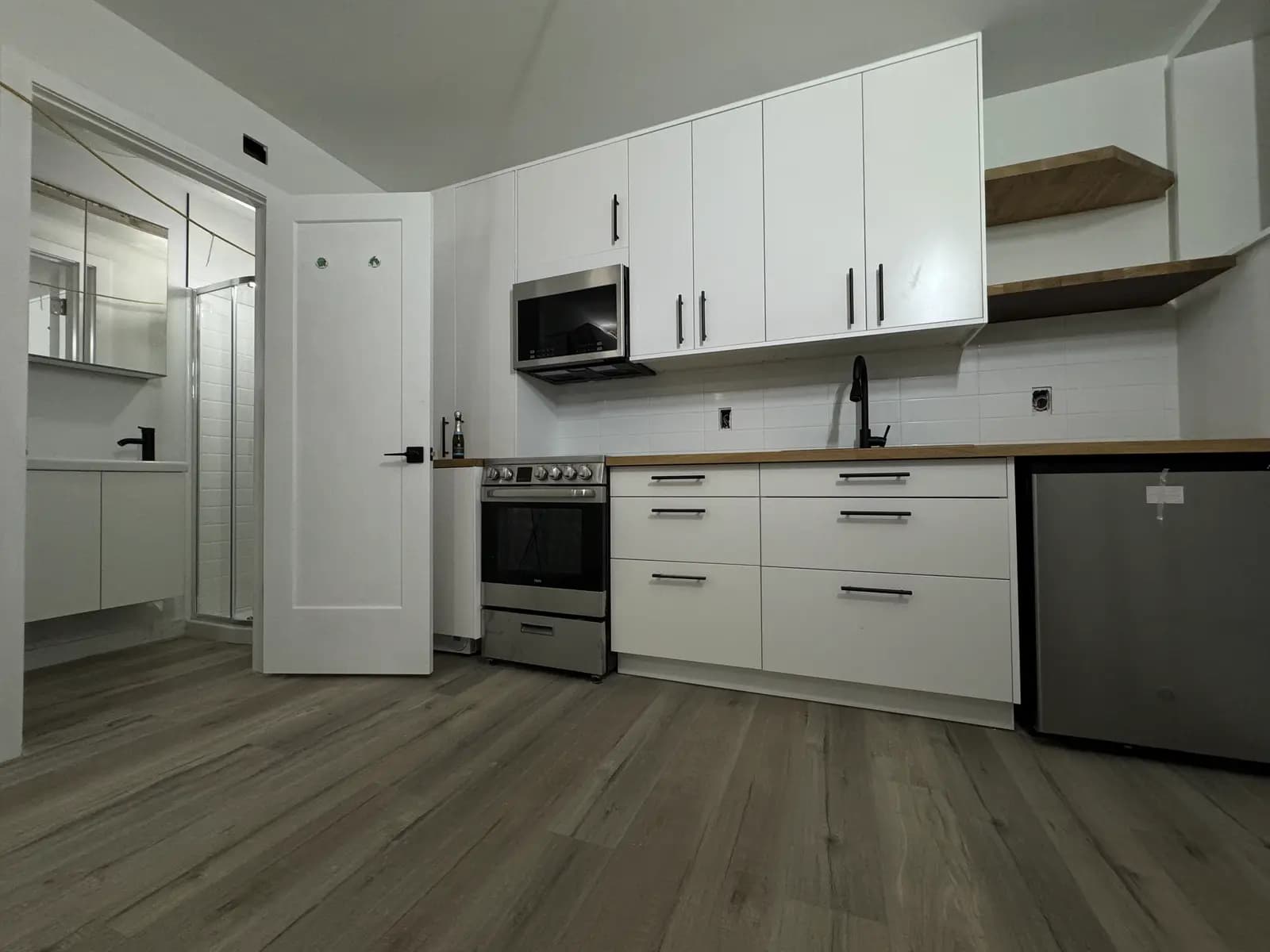 Full kitchen run with stainless appliances, butcher-block counters, and matte-black hardware