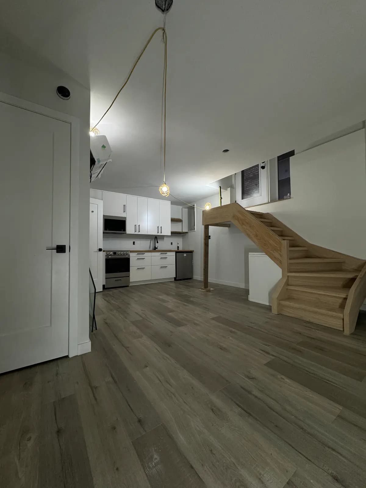 Open suite with the new white kitchen beside a light timber staircase