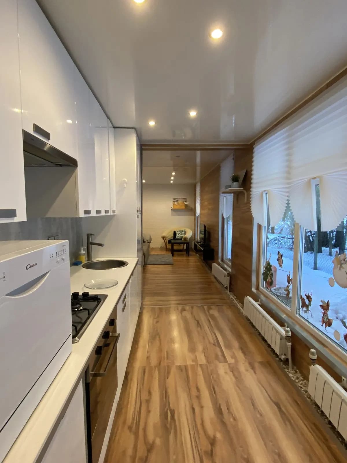 Narrow white kitchen with walnut floor and wall panels and a snowy garden window