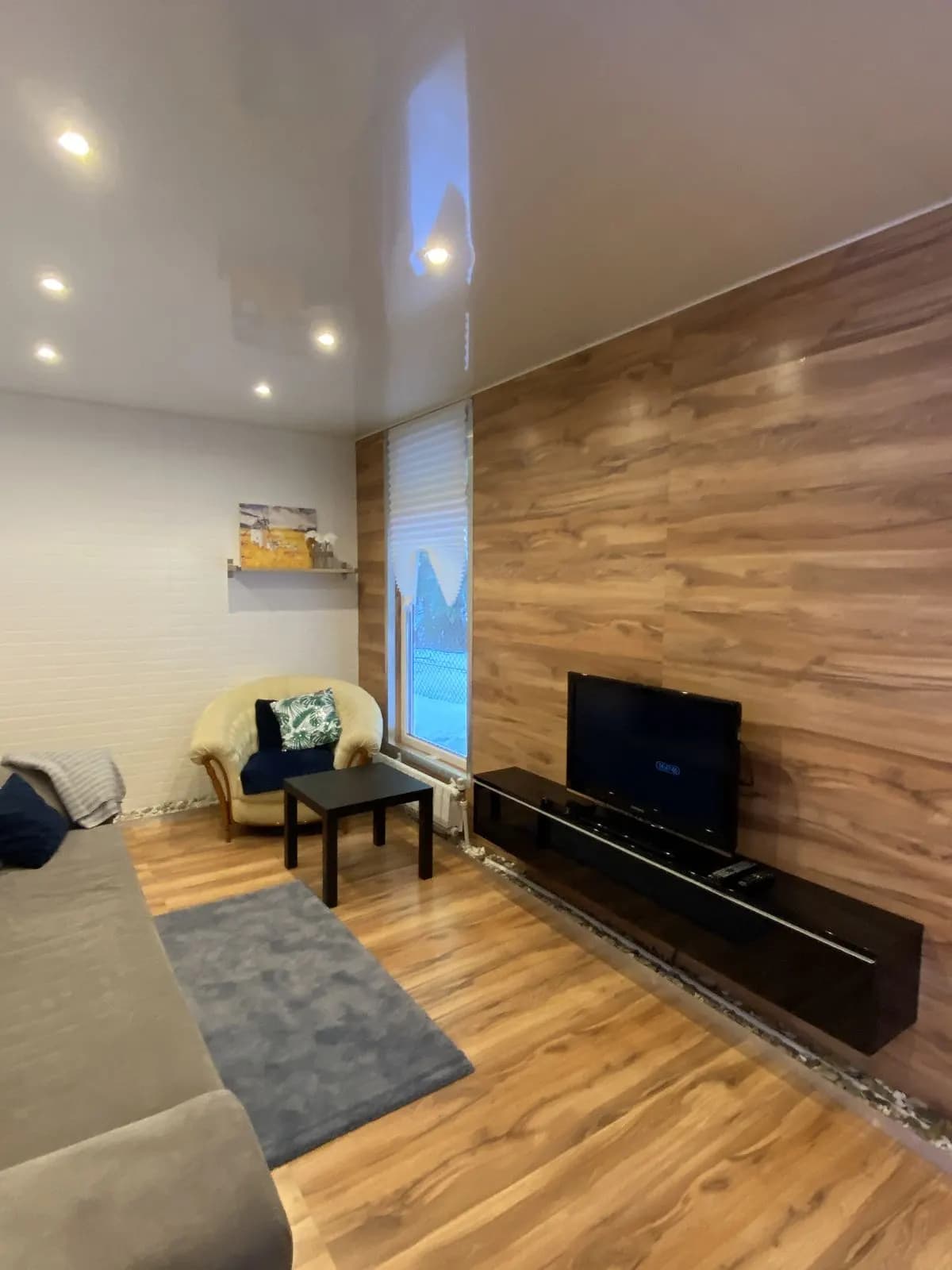 Warm condo living room with walnut wall and layered grey textiles