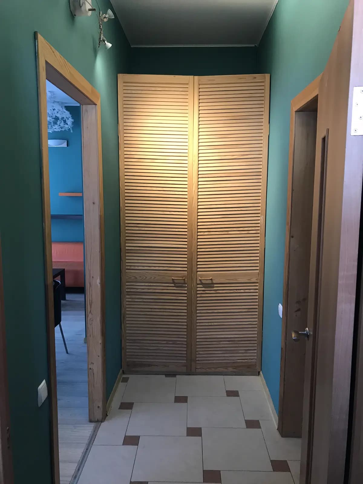 Hallway with teal walls and a louvered wardrobe in warm wood