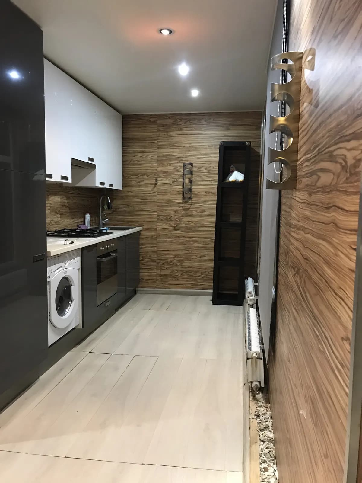 Compact kitchen with dark gloss cabinets, white uppers, and a walnut feature wall