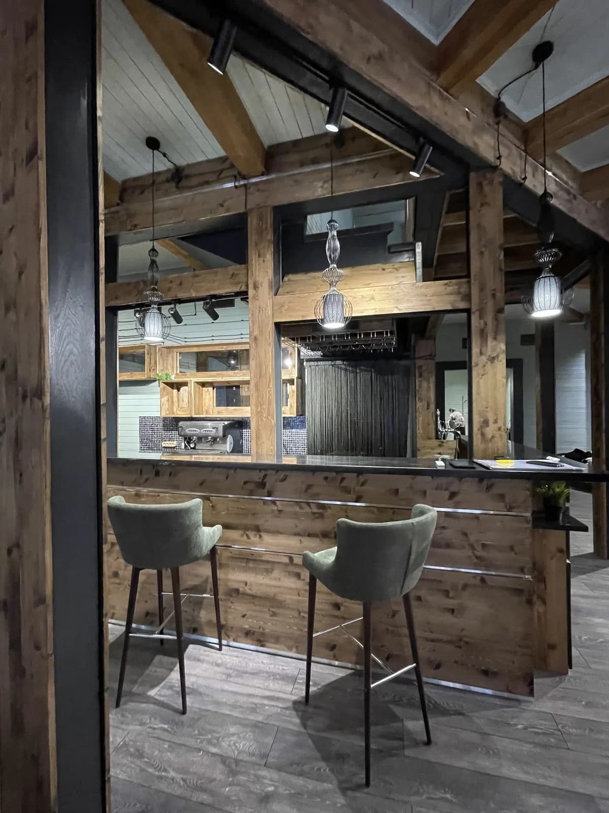 Timber bar with green upholstered stools and pendant lighting