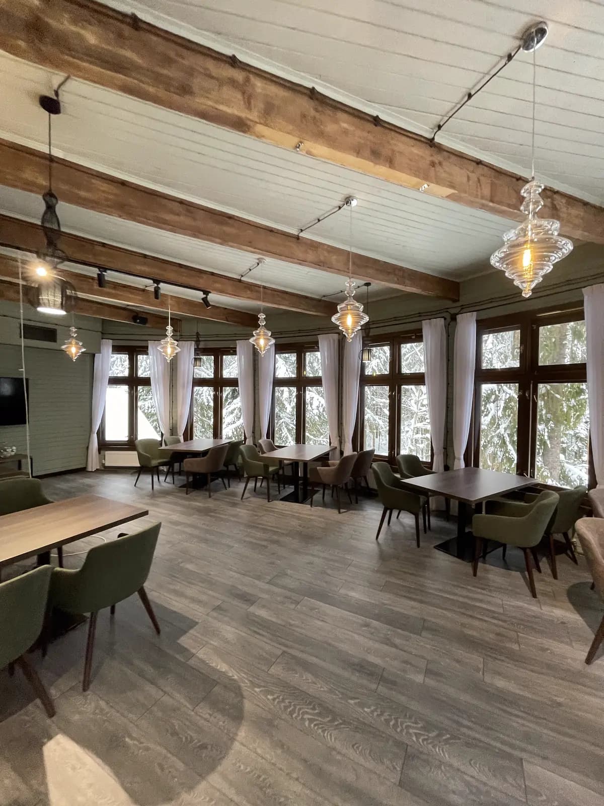The completed dining hall with sage walls, olive chairs, and hand-blown glass pendants