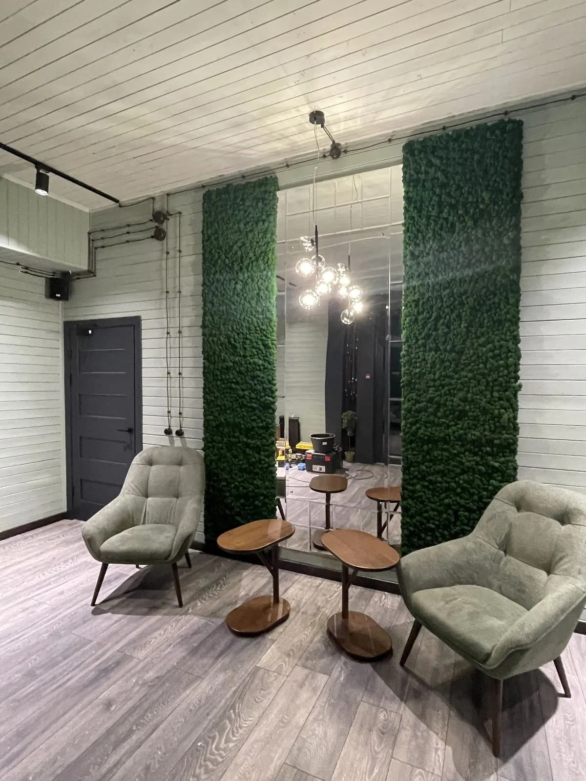 Lounge corner with preserved-moss wall panels and two green armchairs