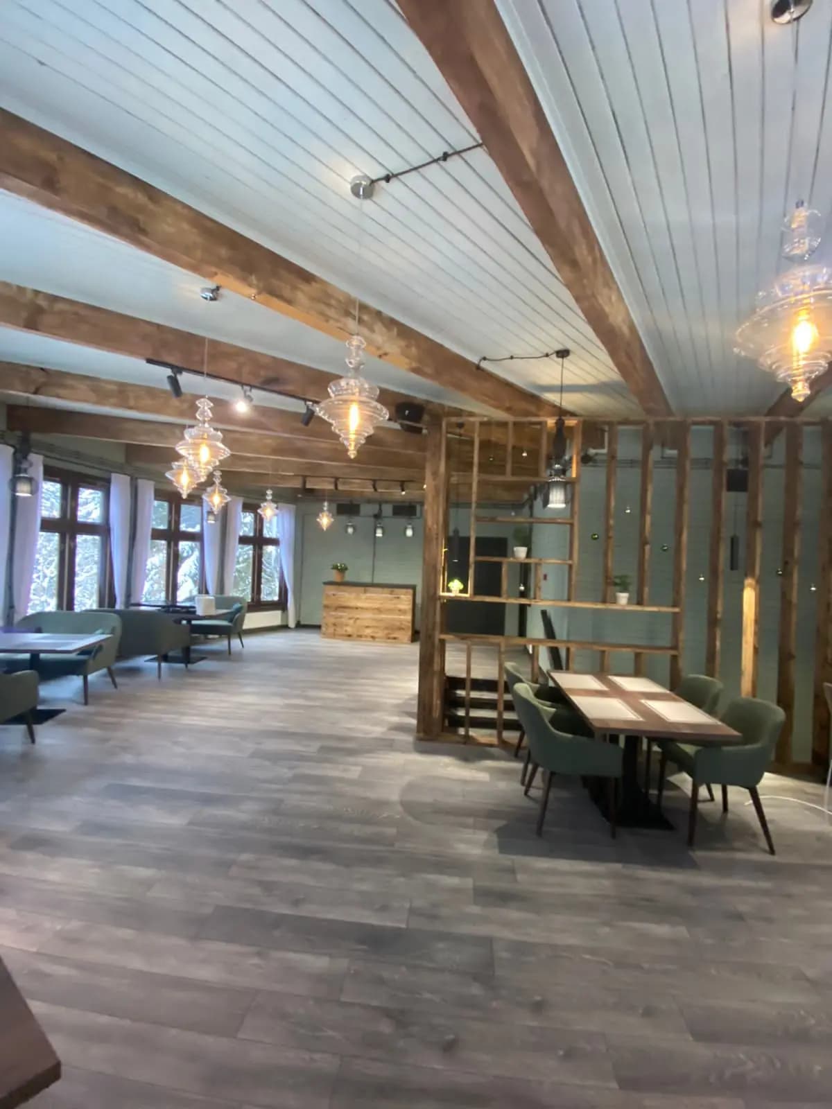 Dining area divided by an open timber partition beneath glass pendant lights