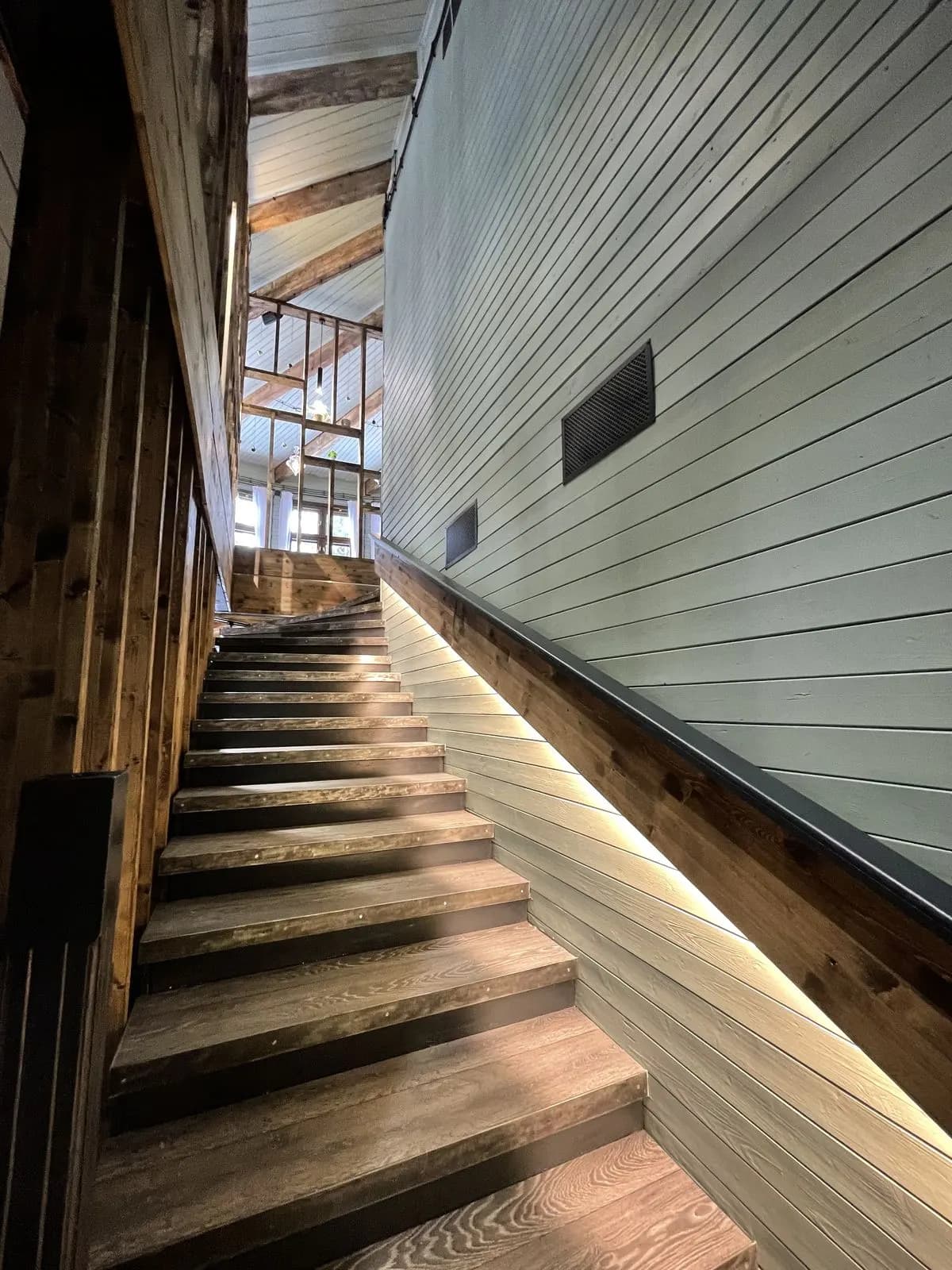 Staircase with underlit timber treads and white plank walls